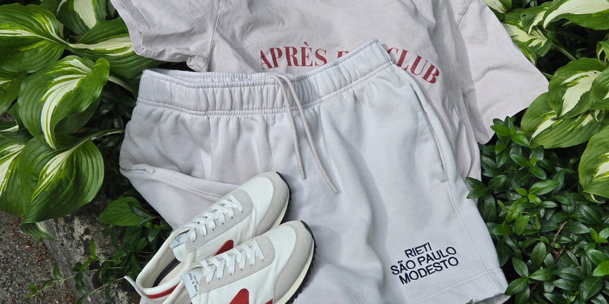Image of Swith Brand Apres Run Club Crewneck Tee and shorts and sneakers laying on green foliage.