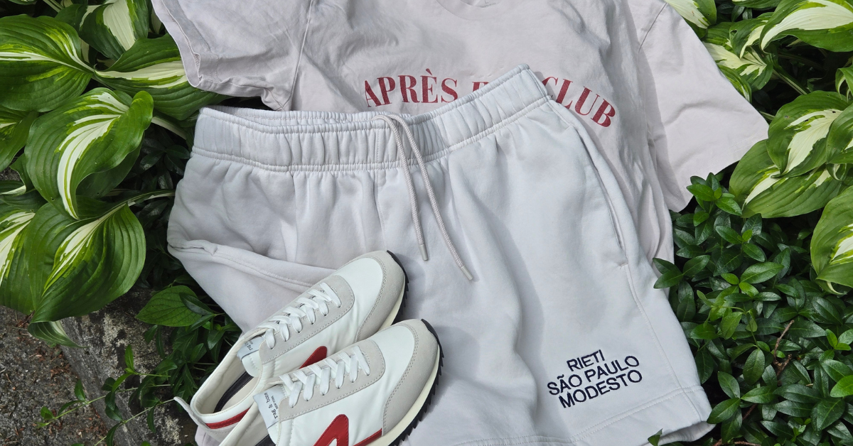 Image of Swith Brand Apres Run Club Crewneck Tee and shorts and sneakers laying on green foliage.