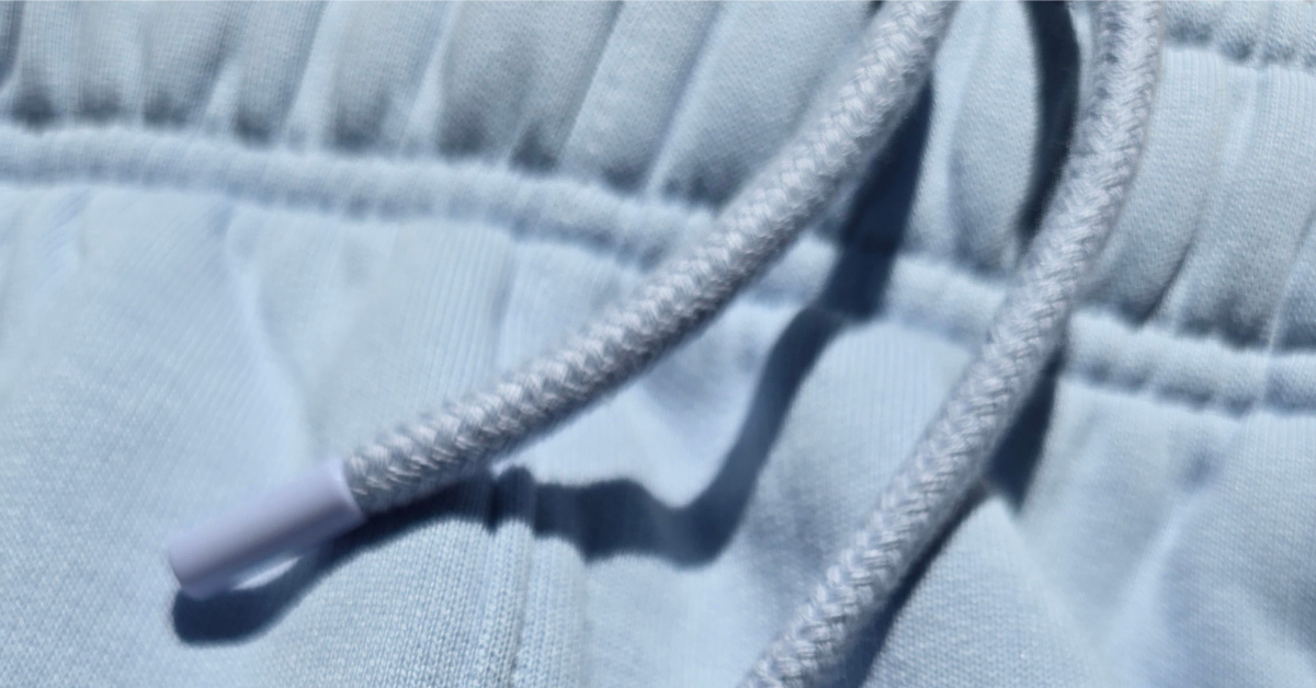 Closeup image of drawcord on light blue sweatpants.